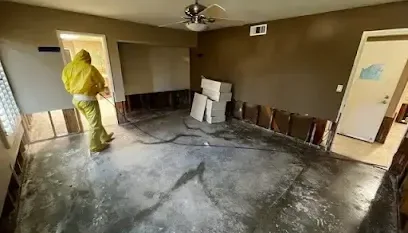 Technician in coveralls working in a room with the lower drywall cut away