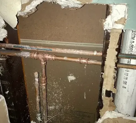Wall opened to expose copper supply pipes after a plumbing failure