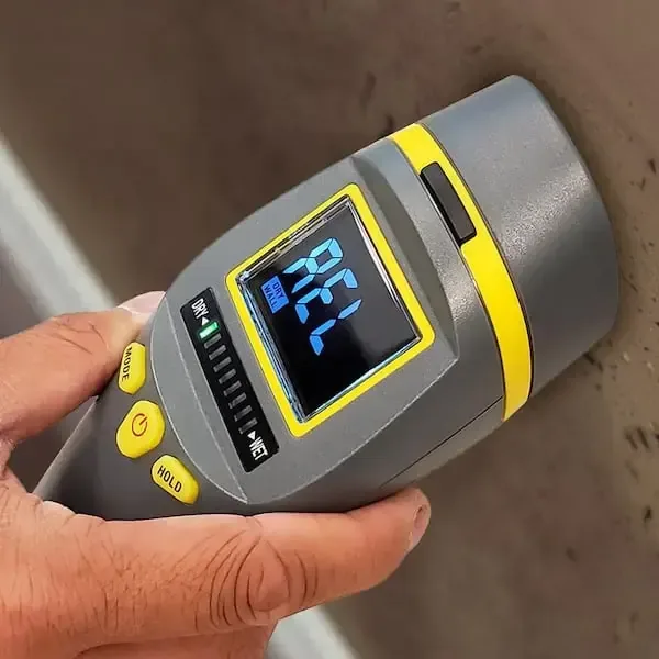 Moisture meter pressed against a wet surface to confirm the reading
