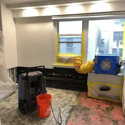 A drying room with air movers set along a wet wall and a dehumidifier in the corner