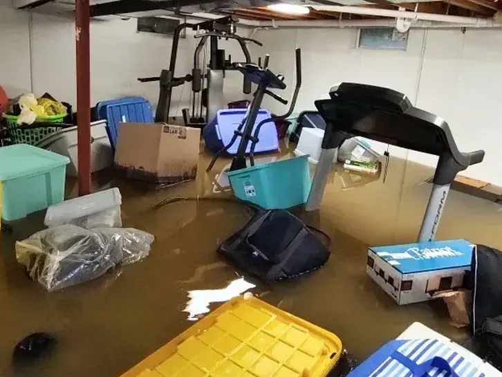 Storage bins, boxes and exercise gear floating in a flooded basement